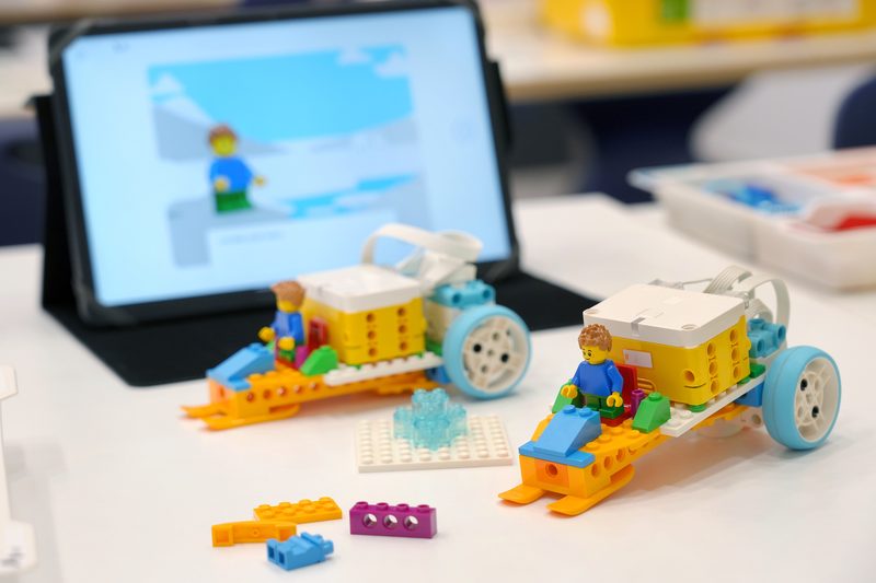 A LEGO Education SPIKE model with a tablet showing the coding app