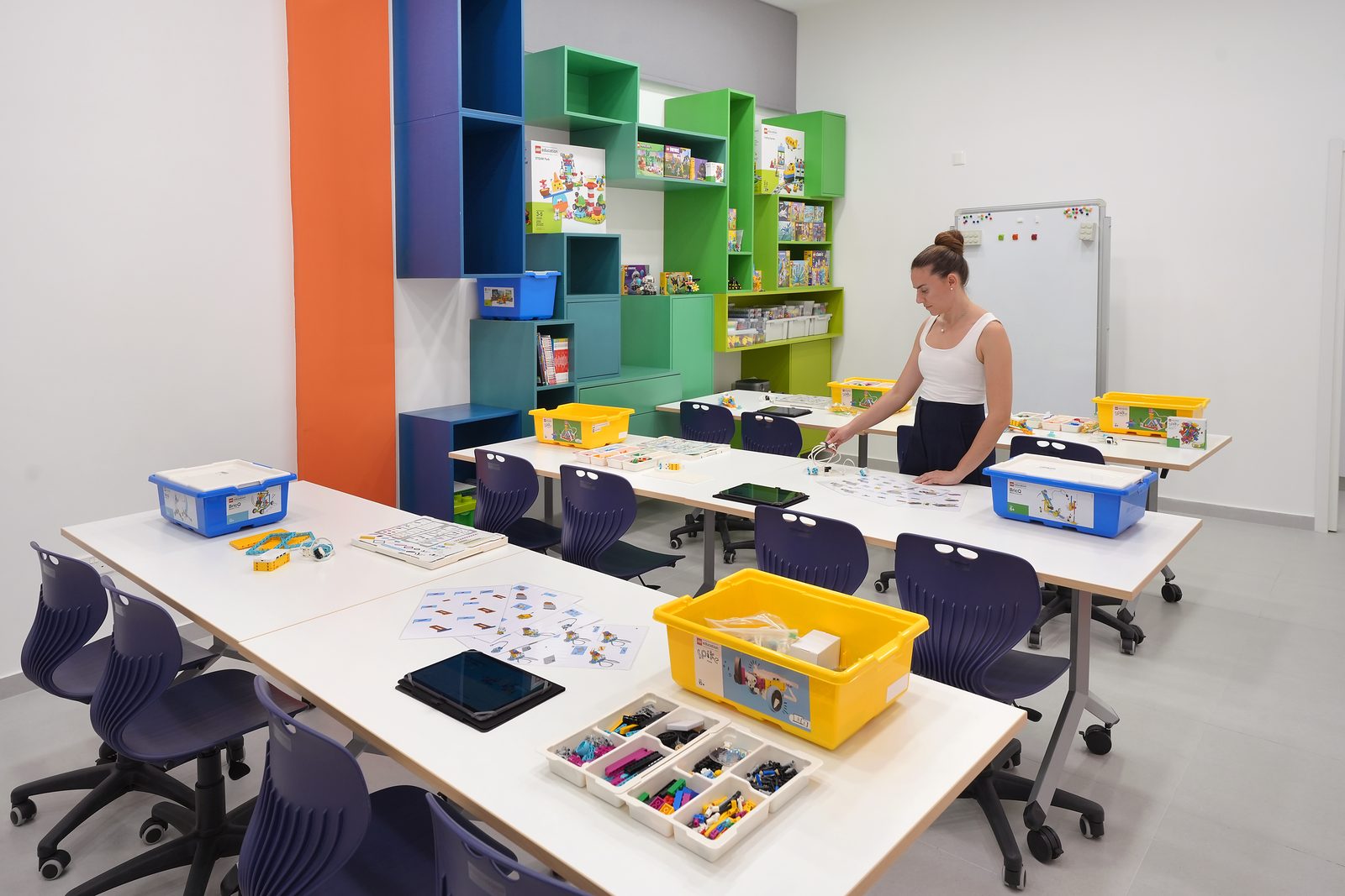 A teacher setting out LEGO Education materials at a classroom table